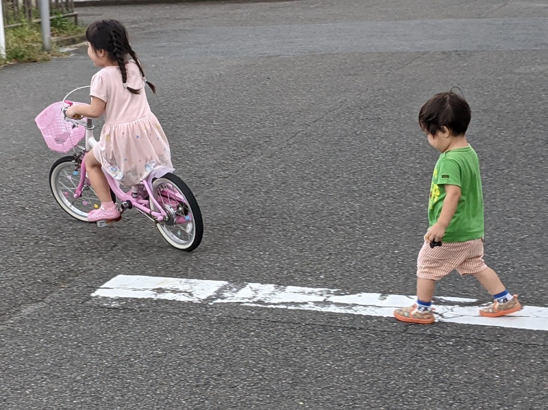 5歳児の乗る自転車を追いかける2歳児